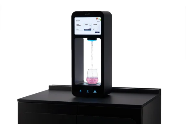 Aquablu Drikkesystem, plassert på disken, dispenserer elegant væske i et klart glass under den intuitive berøringsskjermen.
