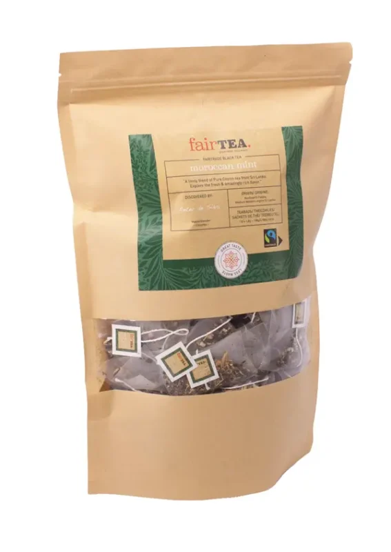En forseglet teemballasjepose i gull merket "FairTea Moroccan Mint" med synlige teposer gjennom et klart vindu.
