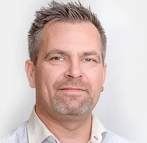 En mann i hvit skjorte står foran et Kontakt Onsite Security-skilt.